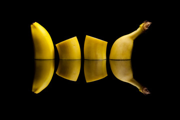 Slicing yellow banana on black reflective background