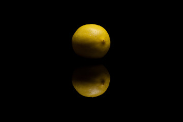 One whole isolated yellow lemon with watter drops on black backg