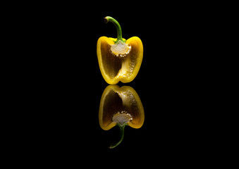 Image of One halved yellow pepper on black reflective background printed on Printed Glass Splashbacks