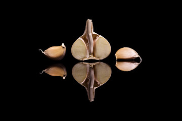 One halved and three peeled garlic isolated on a black backgroun