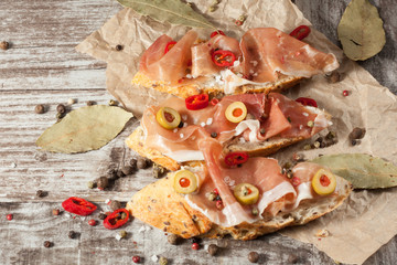 Bruschetta with roasted bell pepper, prosciutto, garlic, olives, spices and herbs. Appetizers.