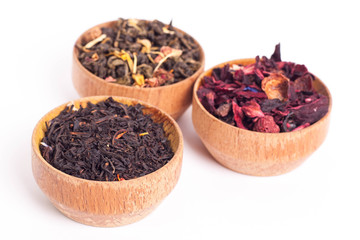 Dry tea in wooden plates, on white background. Leaves of red, green and black tea. Macro photo.