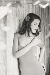 Naklejka premium Attractive young brunette woman with flower in hair talking on mobile phone at wood wall copyspace background
