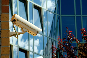 Überwachungskamera an einem Bürogebäude vor einer Glasfassade zum Objektschutz