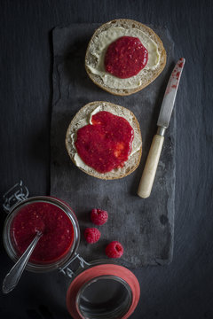 Open jar of raw raspberry & chia jam and bread rolls with butter