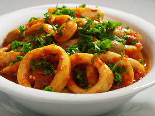 Calamari stewed in tomato and onion sauces with olives, topped w