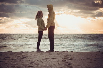 Couple Man and Woman in Love standing on Beach seaside holding hand in hand with Beautiful Sunset sky scenery People Romantic relationship and Friendship concept trendy moody colors