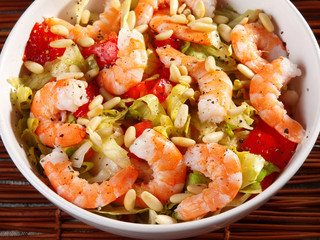 Shrimps salad with iceberg, pine nuts and tomatoes. Shot from ab