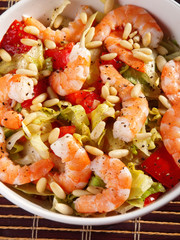 Shrimps salad with iceberg, pine nuts and tomatoes. Shot from ab