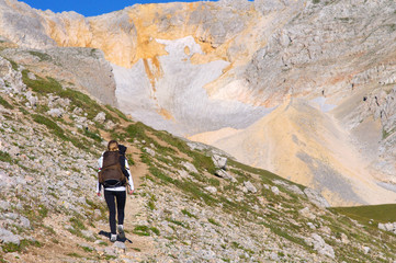 Woman Hiking with Backpack in Mountains on top with glacier snow and rocks on background