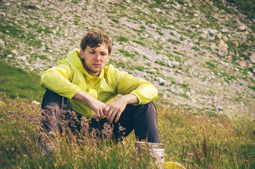 Naklejka na ściany i meble Man relaxing in mountains sitting on grass valley Traveling hiking summer recreation