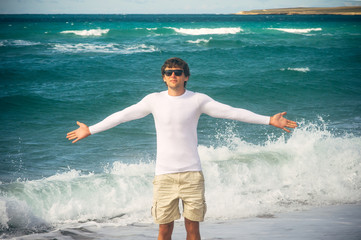 Man Traveler with raised hands outdoor Sea on background Freedom Lifestyle concept