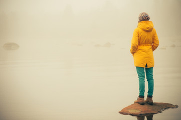 Young Woman standing alone outdoor Travel Lifestyle and melancholy emotions concept  winter foggy nature on background 