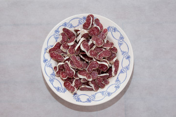 Slices of smoked sausage on a plate isolated on white background