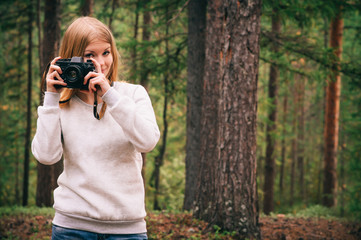 Young Woman with retro photo camera outdoor Travel Lifestyle wild forest nature on background film effects colors