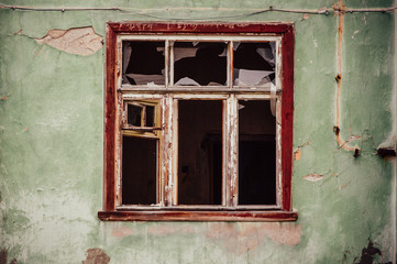 Obraz premium Smashed glass Window with old wooden frame on grunge wall damaged house