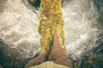 Feet Man trekking boots hiking outdoor with river and stones on background Lifestyle Travel survival concept top view