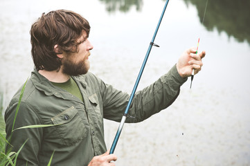 Young Man Fisherman bearded fishing with rod Lifestyle Travel survival concept river on background