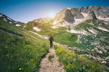 Young Man with backpack hiking outdoor Travel Lifestyle concept with rocky mountains on background Summer vacations