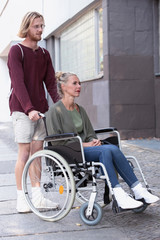 Fototapeta na wymiar woman in wheelchair and man helping her