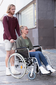 woman in wheelchair and man helping her