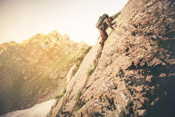 Man Traveler with big backpack climbing on rocks Travel Lifestyle concept mountains landscape on background Summer adventure extreme sport outdoor