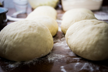 Fototapeta na wymiar Closeup of dough balls on wooden table with flour