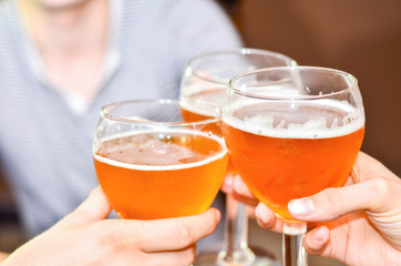 Three people clink glasses with beer