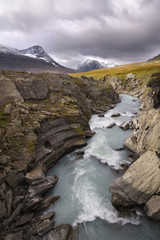 River of melt water flowing in beautiful autumn mountain landscape 