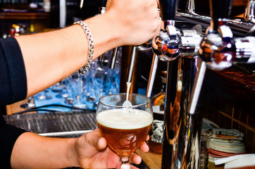 Close up of male hands of bartender, beer tap pouring a lager beer