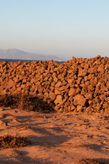 Fototapeta na wymiar Fuerteventura, Isole Canarie: un muretto a secco e il paesaggio marziano sulla strada per Majanicho, nel nord dell'isola, il 3 settembre 2016