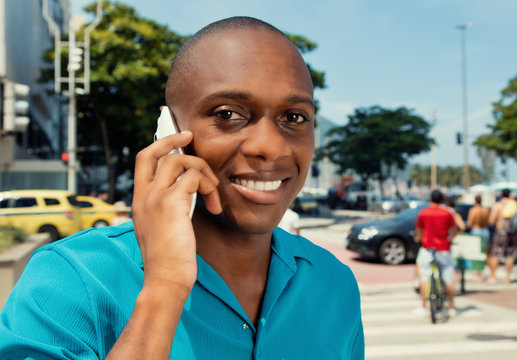 Happy African Man Using Cellular In A Warm Cinema Look