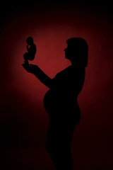 Pregnant woman holding in her hands the symbol of embryo