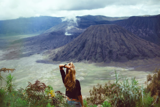 pretty girl the tourist, the hipster with a backpack posing on a volcano and looking into the distance,the atmosphere of adventure,of searching,of wandering,a portrait of the traveler,outdoor,close up