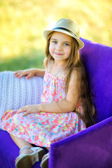 the girl smiles and poses in a chair outdoors