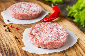 Raw fresh burger meat patties on wooden chopping board