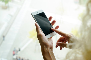 A close up photo of a female hands holding a modern smartphone on a blurred background. A cropped image of a mobile phone in the hands of a woman shopping online.