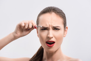 Girl plucking her brows painfully