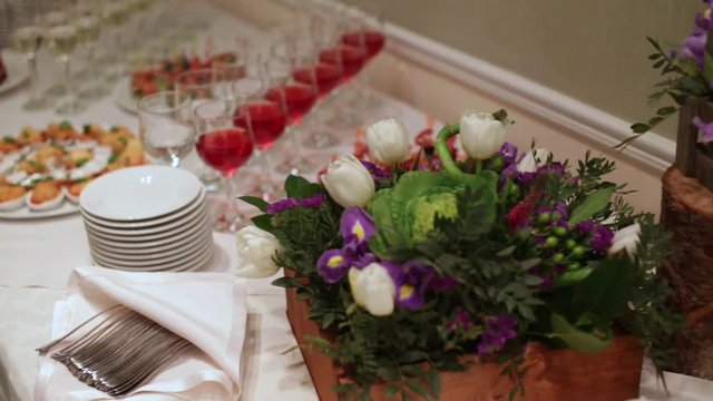 The glasses are arranged beautifully. table decorated with flowers. in the background are snacks at the buffet