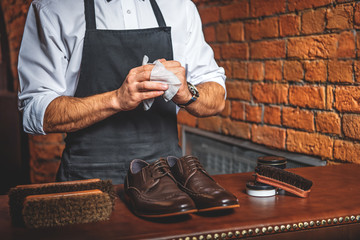 craftsman wipes hands after polishing boots