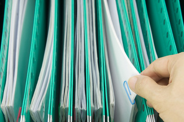 Man pick paperwork from green suspension folder hang in cabinet