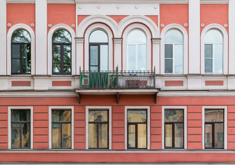 Fototapeta premium Several windows in a row and balcony on facade of urban apartment building front view, St. Petersburg, Russia.