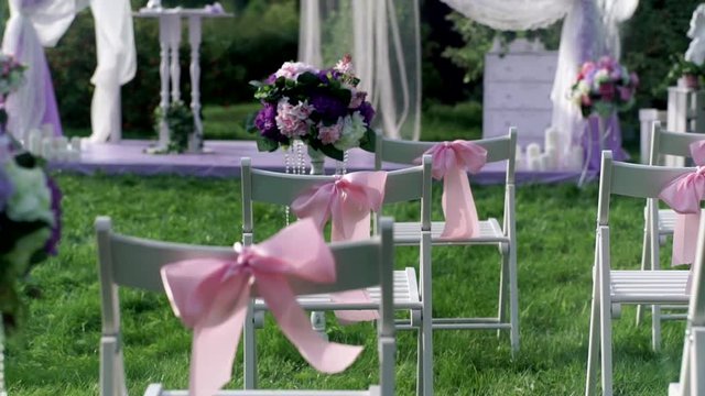 White chairs with pink bows close up outdoors at wedding verinke. Wedding decorations.