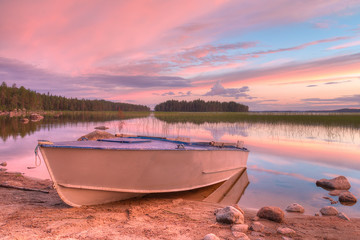 The boat on the shore of lake in evening with beautiful sky.