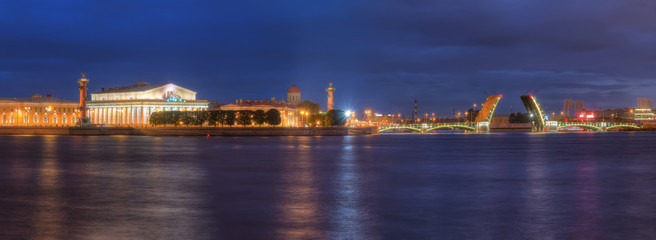 Night panoramic view on illumunated open Birzhevoy Bridge, Neva River and Old Stock Exchange, St. Petersburg, Russia.