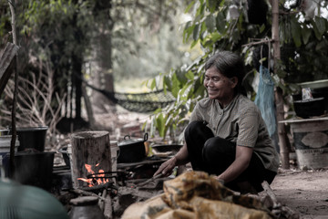 The old woman was a fire to cook dinner. As shown by the country in the Southeast Asian.