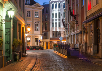 Naklejka na ściany i meble Night view of a street in Riga that is the capital and largest city of Latvia, a major commercial, cultural, historical and tourist center of the Baltic region 