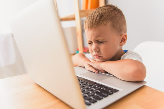 Cute little boy using laptop at home