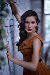 Pretty slim woman with yellow dress posing against stone wall