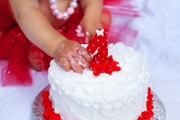 Hand of little child destroys birthday cake